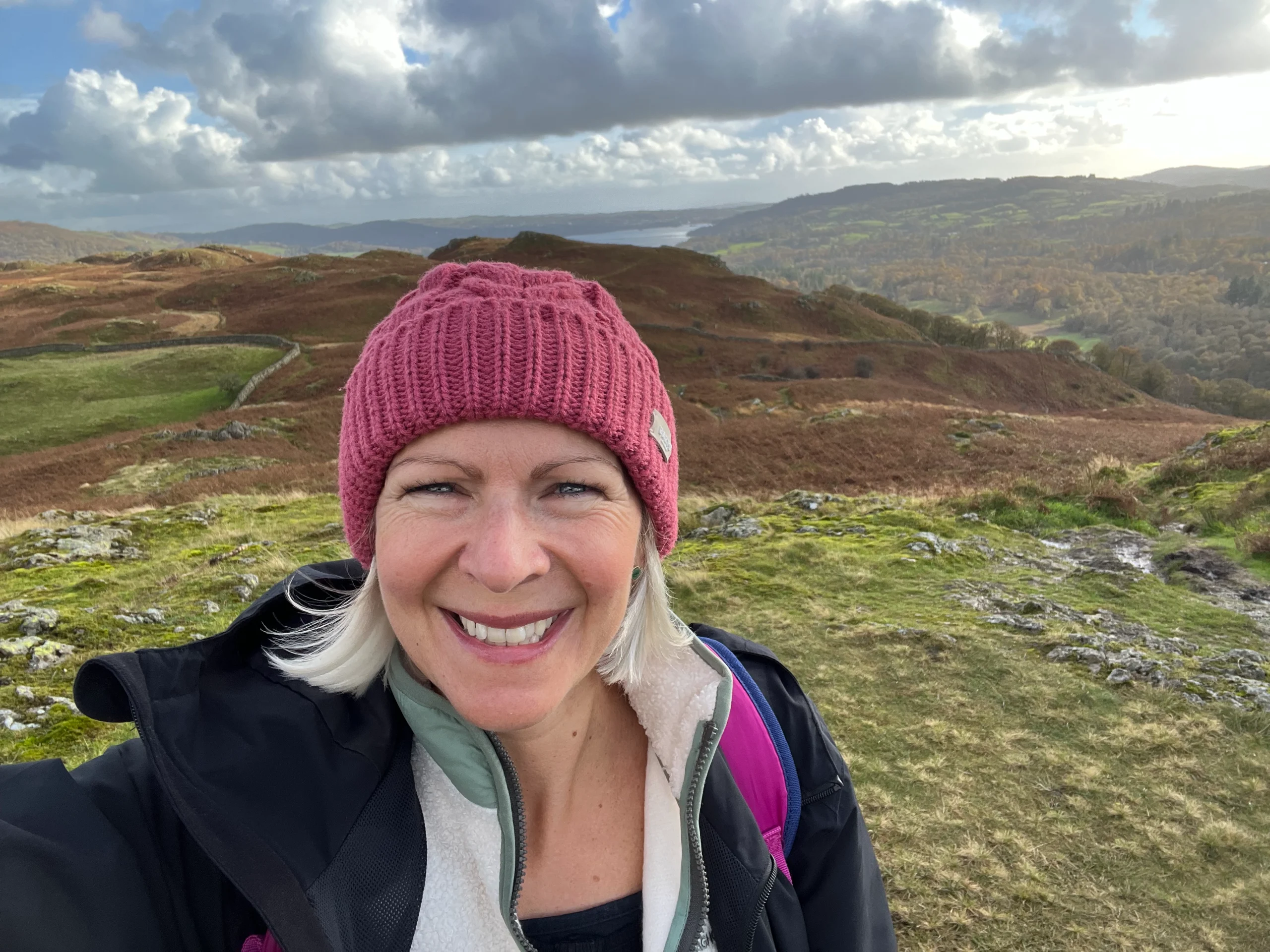 Outdoor portrait of Marsha wearing a hat, surrounded by a scenic mountain landscape.