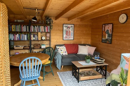 Inviting cabin room with natural wood finishes, a blue chair, round table, bookshelf, and couch